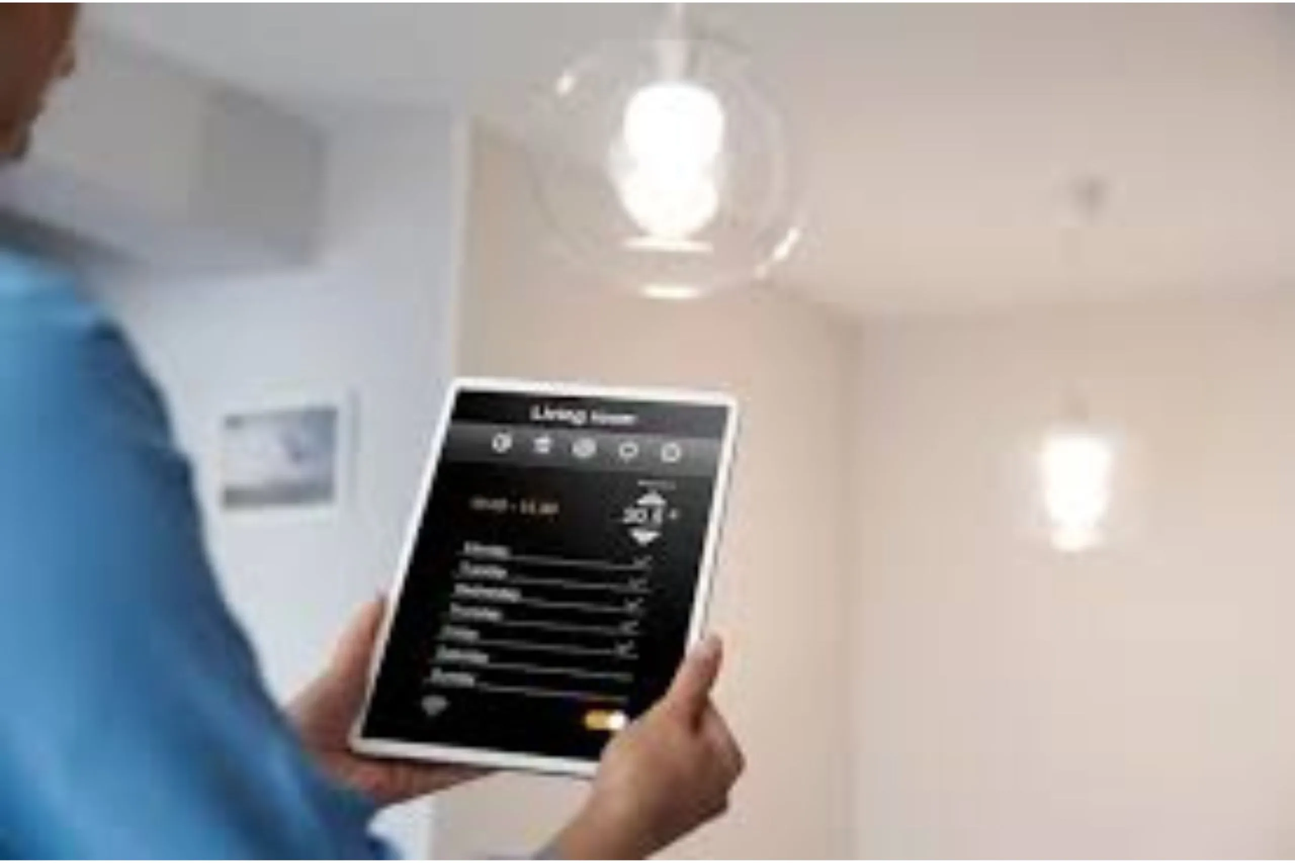 A person adjusts settings on a tablet for their wireless alarm system and smart home lighting