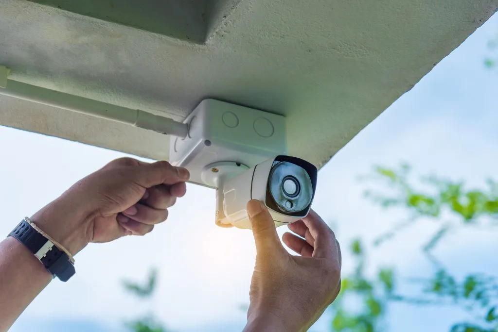 A person is installing a security camera under a shelter