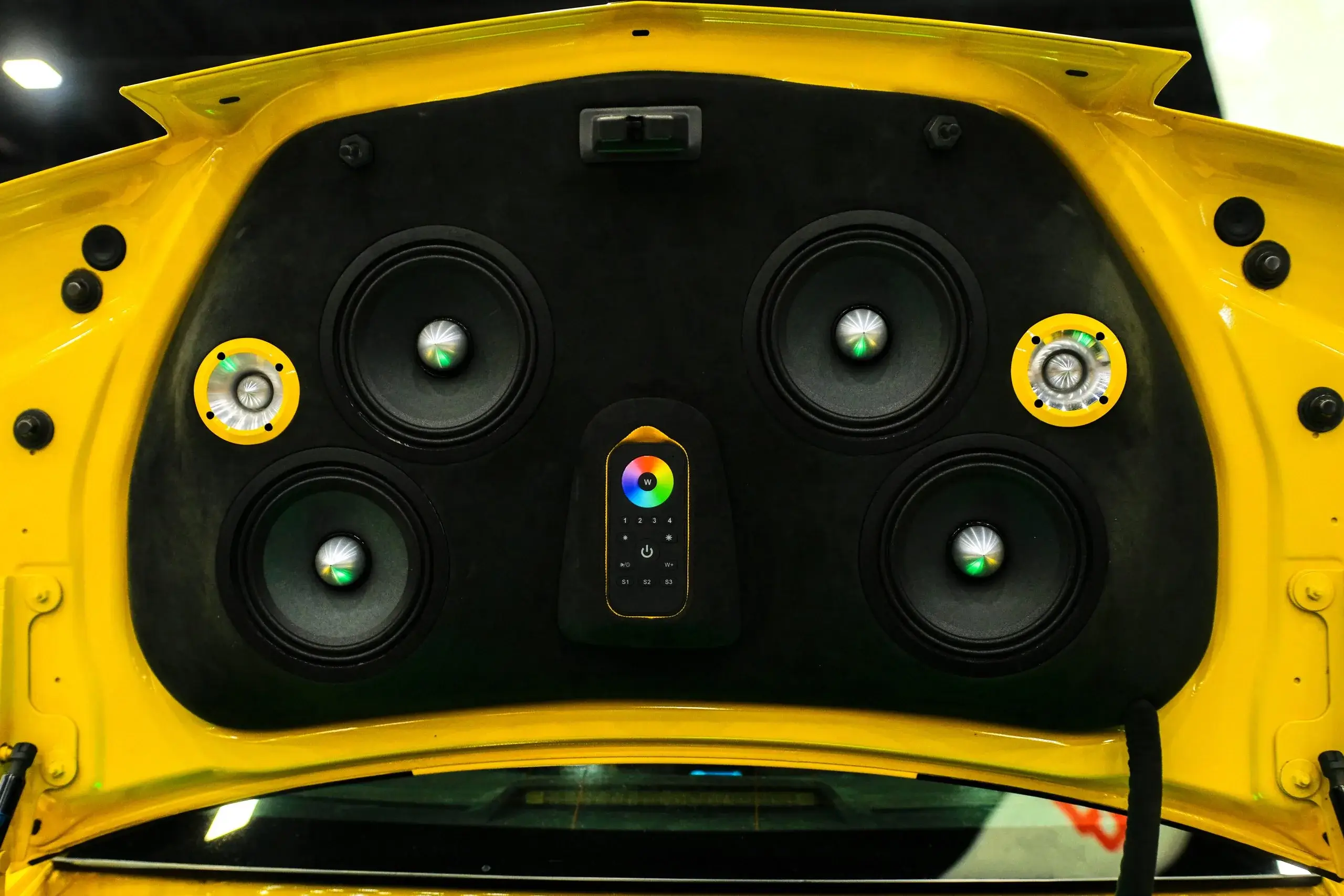 Vibrant yellow car trunk displays an impressive array of colorful car audio speakers