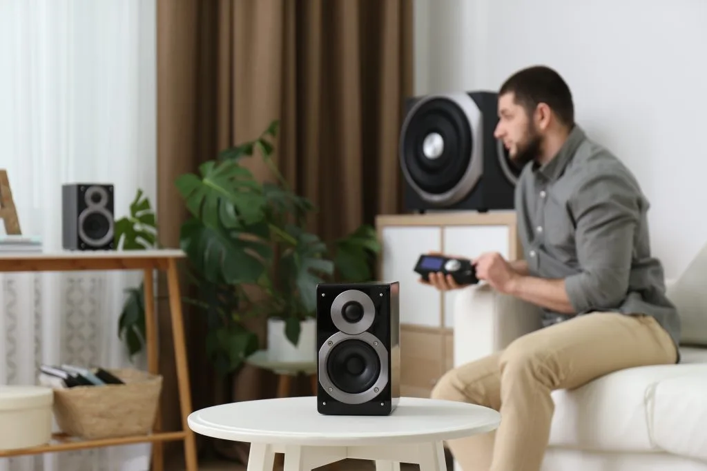 A man adjusts custom audio visual systems while relaxing on a couch in a cozy living room