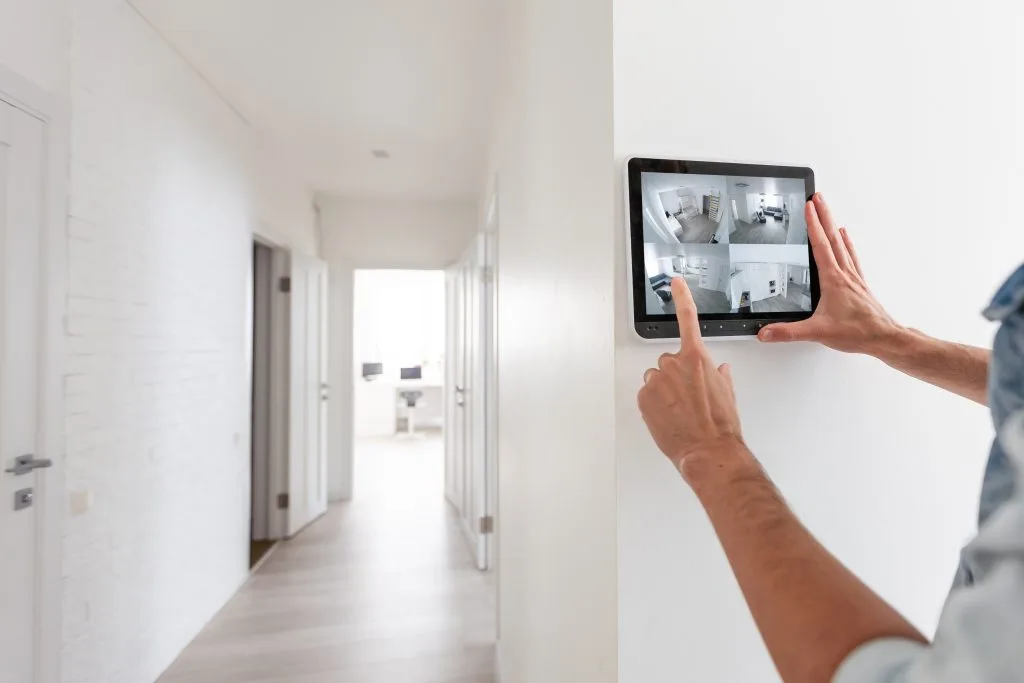 A person uses a tablet to monitor video security systems in a hallway