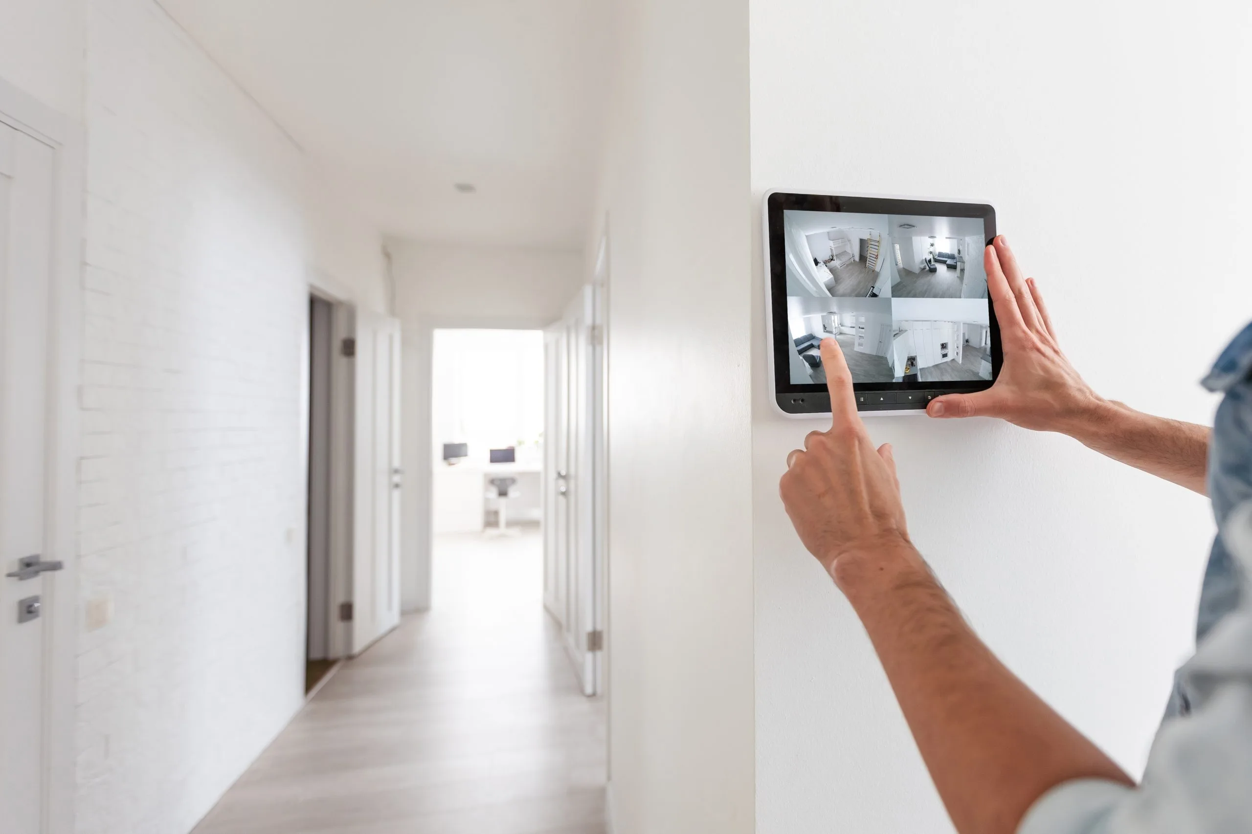 A person uses a tablet to monitor video security systems in a hallway