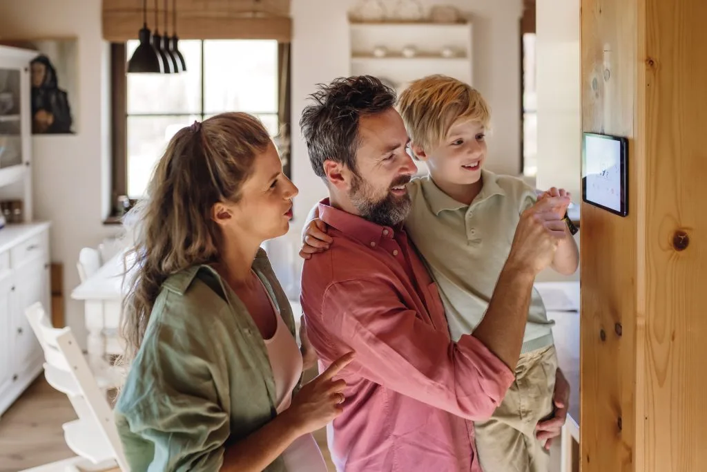A family joyfully interacts with a touchscreen device in a cozy home setting