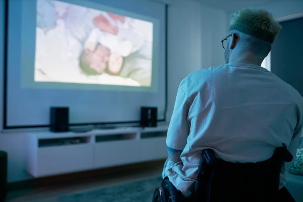 Custom audio visual systems enhance the experience for a person in a wheelchair watching a projected video