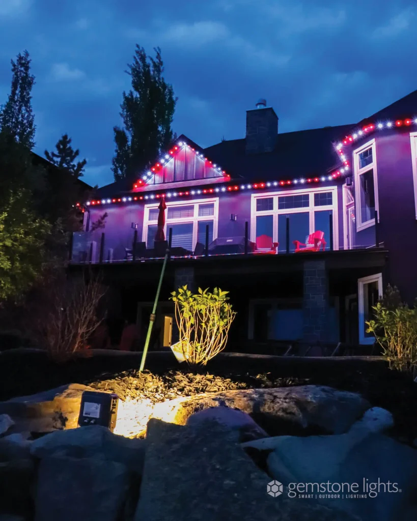 Colorful outdoor lights illuminate a modern home against a twilight sky