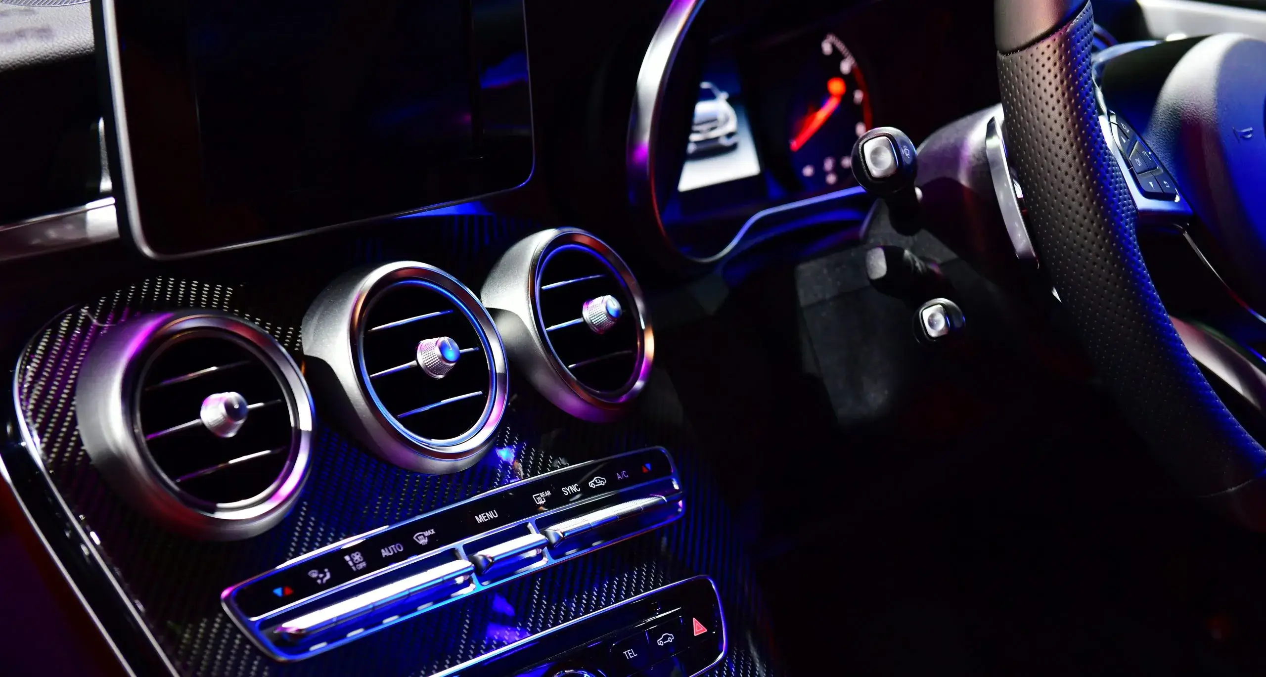 A sleek car interior features modern controls illuminated by ambient lighting