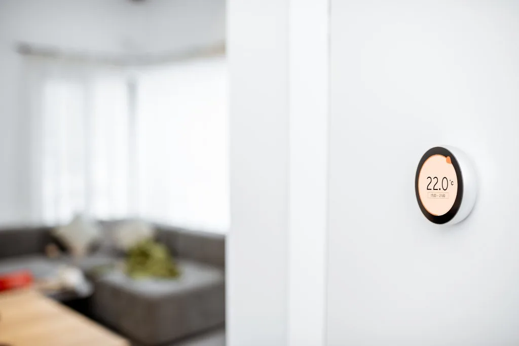 A modern thermostat displays the temperature in a bright, airy room