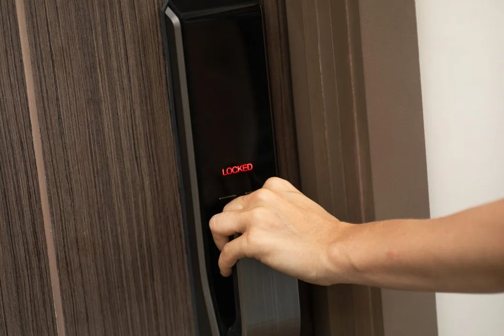 A hand is touching a digital keypad on a wooden door