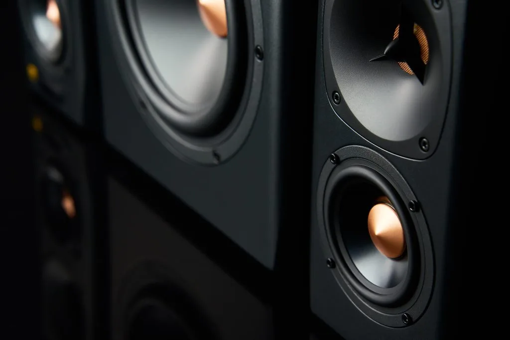 Black speakers with copper accents are positioned closely together, showcasing their intricate design