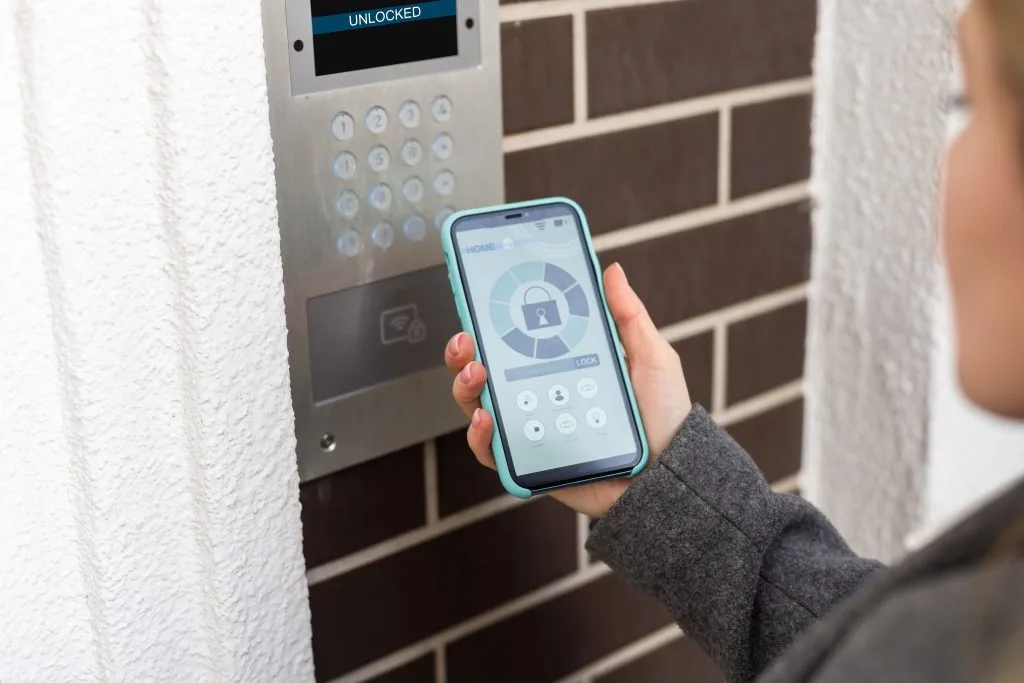 A person uses a smartphone to interact with a wall-mounted access panel