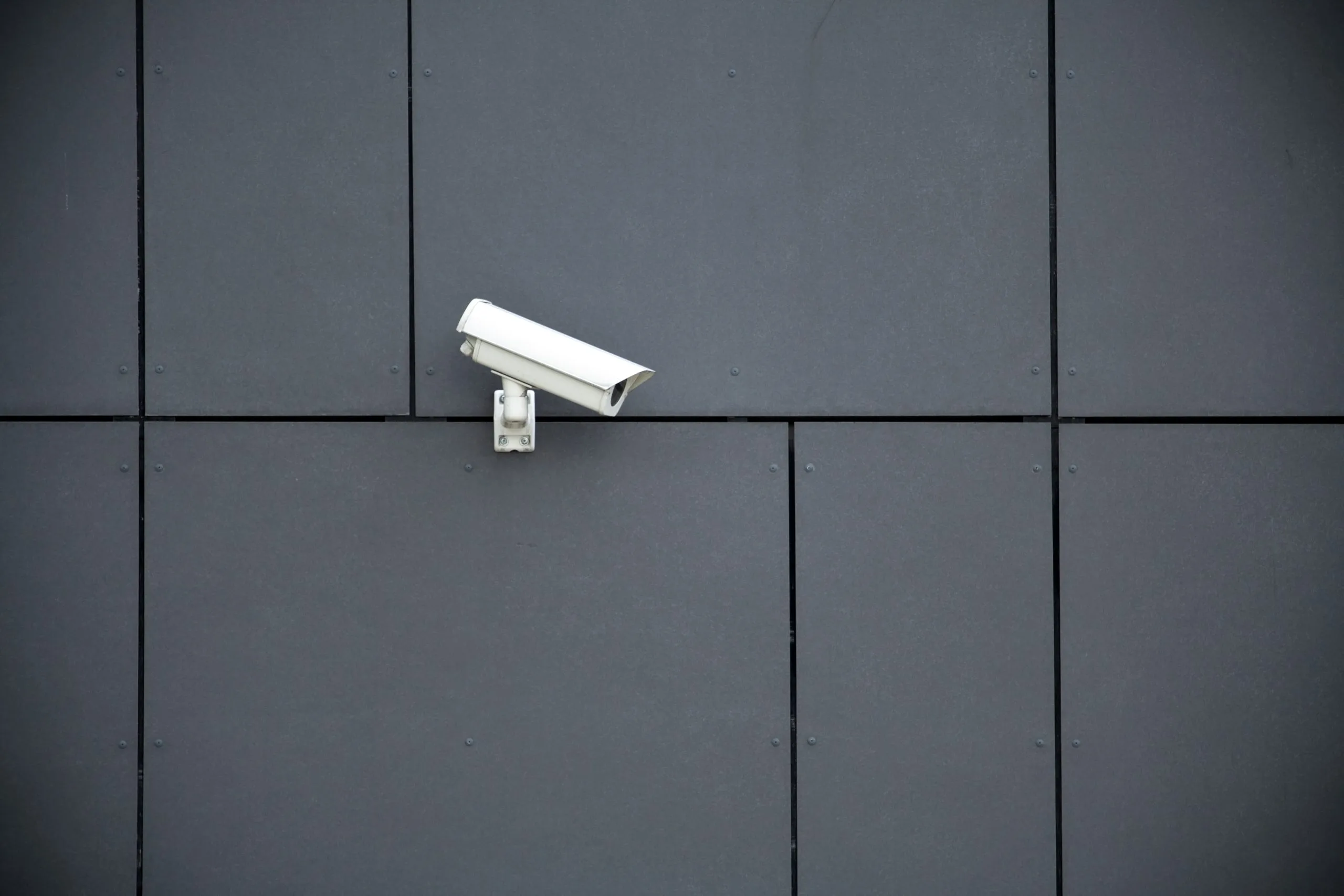 A security camera is mounted on a modern, gray wall