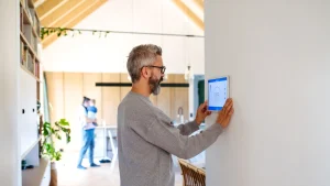 A man interacts with a tablet while another person is seen in the background